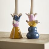 Swift Bird Stoneware Candle Holders set of 2, ceramic bird figures with dotted bodies holding leaf-patterned flower cups, one on a mustard cone base, one on a blue stacked base, with taper candles.