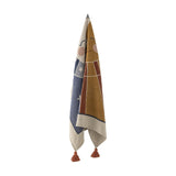 Sun Cotton Throw hanging vertically, woven cotton blend blanket in mustard and navy with a smiling sun face, stars, and rust tassels, shown against a plain white background.