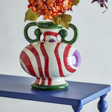 Betiva Striped Stoneware Vase 25.5cm in multicoloured with green loop handles and red striped body on a blue side table, styled with dried flowers against a light background.