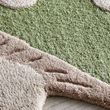Close-up of the Mushroom Wool Rug in green, showing tufted wool texture with raised cap spots and a beige gilled edge against a wood floor.