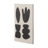 Lutton Stoneware Wall Decor in white, a rectangular ceramic panel with four black organic shapes—leaf, bud, hourglass and stacked pebbles—shown at an angle on a plain background.