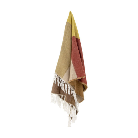 Ara Throw in brown, draped with colour-blocked panels of yellow, rust, beige and brown, finished with knotted fringe, shown against a plain white background.
