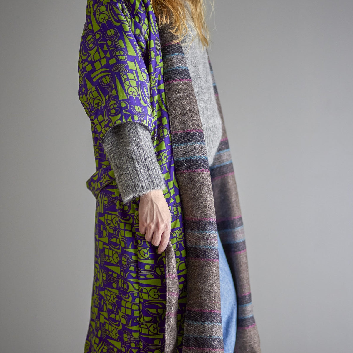 Rieti Striped Kimono in Grey, shown reversible with woven grey striped fabric on one side and a purple-green geometric print on the other, worn open with a tie belt against a plain grey background.