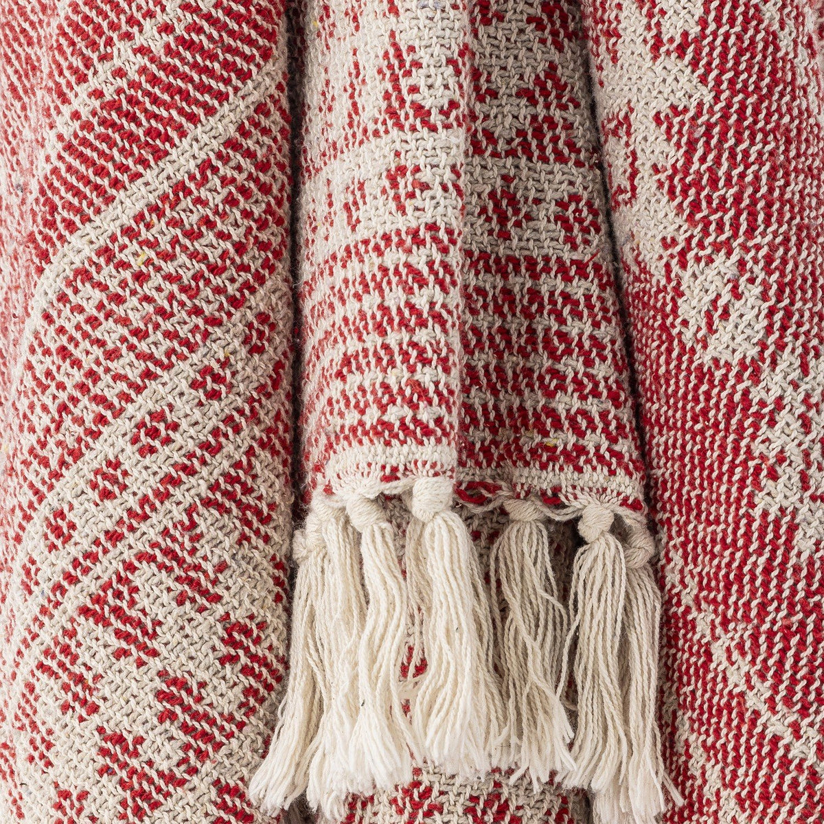 Close-up of the Oia Snowflake Cotton Christmas Throw in red, showing woven snowflake and stripe patterns with cream knotted tassel fringe.