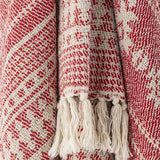 Close-up of the Oia Snowflake Cotton Christmas Throw in red, showing woven snowflake and stripe patterns with cream knotted tassel fringe.
