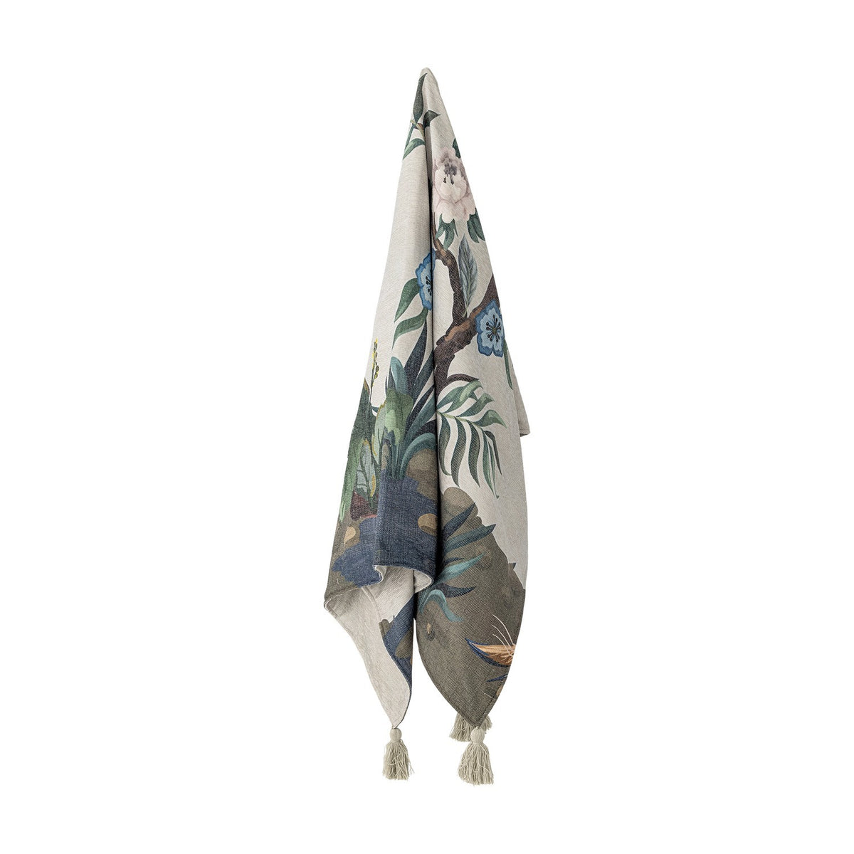 Peacock Throw in green, printed fabric with garden scene of floral branches and foliage, finished with tassels, hanging against a plain white background.