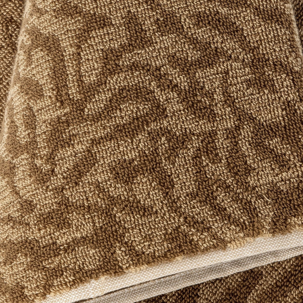 Close-up of the Kaysa Cotton Towel in brown, showing a branching coral-like woven pattern in looped cotton pile with a woven trim edge.