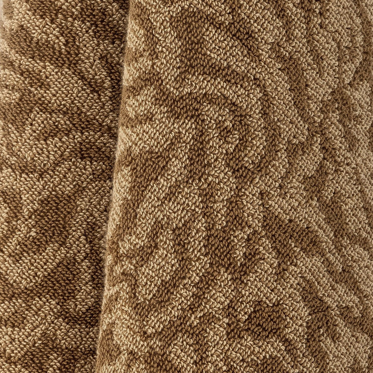 Close-up of the Kaysa cotton bath towel in brown, showing its soft looped pile with a textured, curling pattern in lighter and darker brown tones.