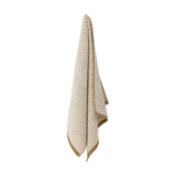 Malou Cotton Towel in Natural hanging against a white background, showing a woven geometric diamond pattern in cotton with a mustard-coloured border edge.