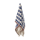 Rimme Cotton Throw in multi hangs against a white background, showing a navy and cream geometric wave pattern with a rust-coloured border and knotted fringe.
