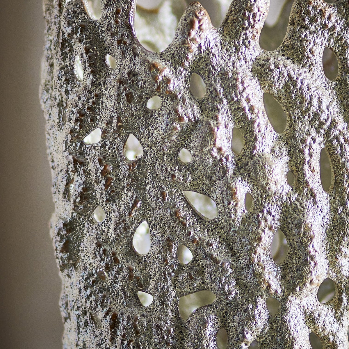 Close-up of the Eunice Stoneware Vase 37cm in white, showing its deeply pitted, coral-like surface pierced with irregular open holes and an uneven rounded rim.