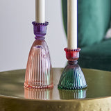Shilo ribbed glass candle holders set of 2, tall purple-to-pink and shorter red-to-green pieces with beaded bases, holding white taper candles on a brass side table.
