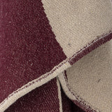 Cimmi Christmas Throw in Multi, close-up of woven fabric showing burgundy and cream curved colour-block pattern with fine flecked texture and stitched edge.