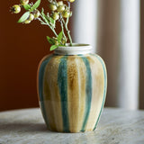 Rahima Crackle Stoneware Vase 20cm with hand-painted teal and ochre stripes and a crackle glaze, round body and white rim, holding a leafy berry sprig on a marble surface.