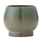 Imke stoneware plant pot with rounded body on a short footed base, finished in a green reactive glaze that fades to beige, shown on a plain white background.