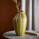 Abella Speckled Stoneware Vase in yellow, 35.5cm tall with a ribbed, asymmetrical silhouette, shown holding budding branches on a stone side table.