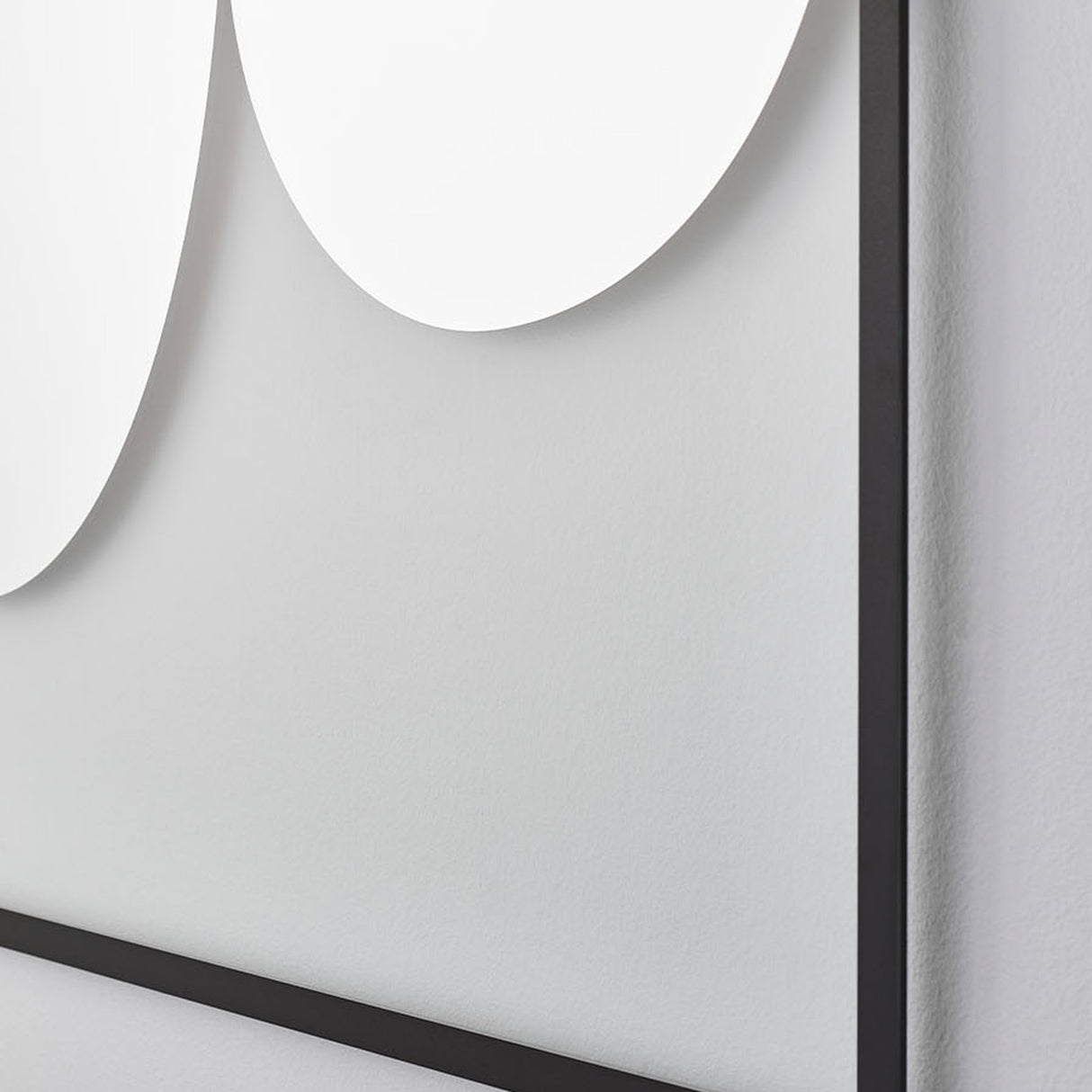 Close-up of the two rounded forms meeting on the glass, the slim black frame crossing behind where they overlap.