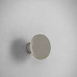 Arid A/01 round aluminium LED wall light with fine vertical fluted disc face in Textured Pebble Grey, mounted on a short cylindrical stem against a plain light background.