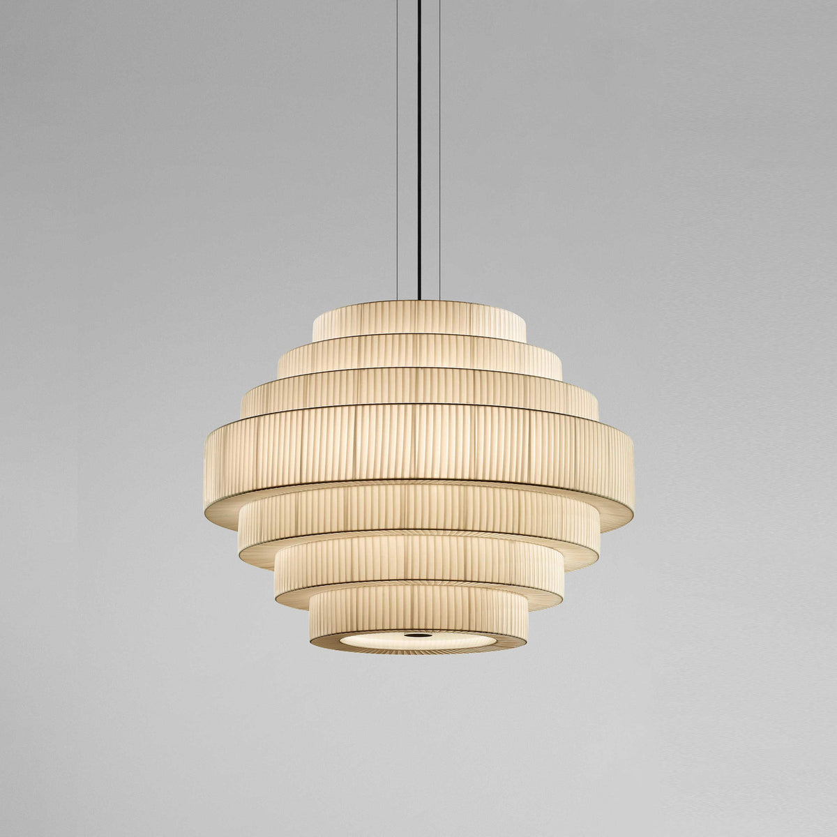 Mos 03 Ribbon Tiered Pendant Light with stacked pleated translucent ribbon rings forming a rounded, dome-like shade in cream, shown lit on a plain grey background.
