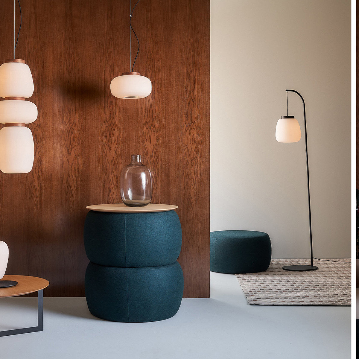 Misko S15 glass drum pendant light with white opal shade and black cable, shown with a floor lamp, teal pouf and side table in a modern living room.