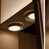 Ring C45 Glass Ring Ceiling Light in black finish, two flush-mounted circular fixtures with offset inner discs casting a warm glow, shown recessed into a wooden ceiling nook.