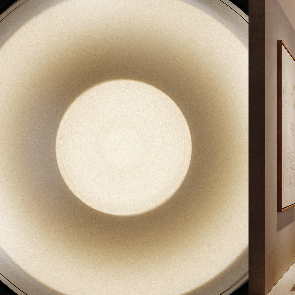Close-up of the Bug Halo recessed LED downlight in Brushed Titanium, showing its deep round reflector glowing warm white, with a hallway and framed artwork visible alongside.