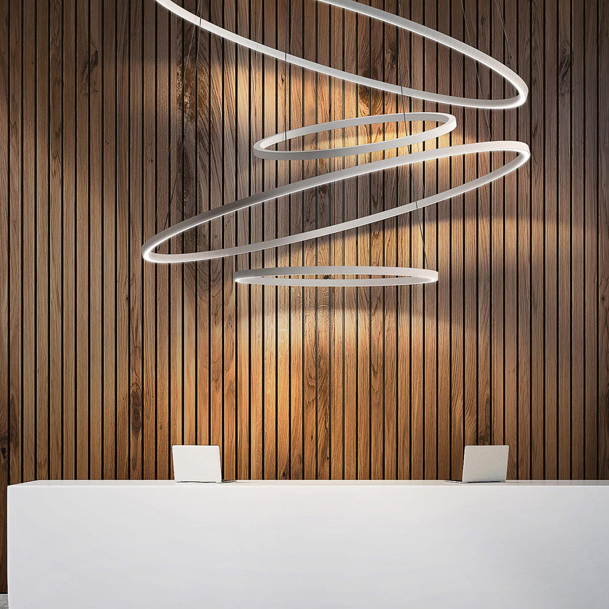 Brooklyn Round 360° Aluminium Ring LED Pendant Light in white, multiple tiered circles suspended above a reception desk against a wood-slat wall.