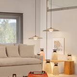 Nans Portable M/49 lantern-style table lamps with woven brown lattice shades and wooden carry handles, glowing warmly on wooden plinths in a living room beside pendant lights and a beige sofa.