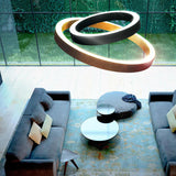Golden Ring Aluminium LED Pendant Light, 183cm, in black and gold finish with two interlocking illuminated rings, hung above a living room seating area.