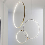 Zero Round Vertical Ring Pendant Light, 50cm circular LED design in brushed brass, shown with black and silver ring pendants suspended from thin cables in a white interior.