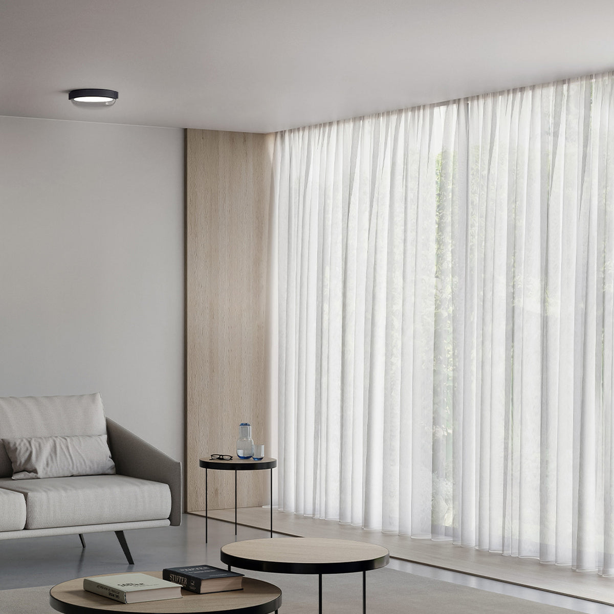 Beaded C round flush ceiling light with black trim and grey glass diffuser, mounted in a neutral living room with sheer curtains and wood panelling.