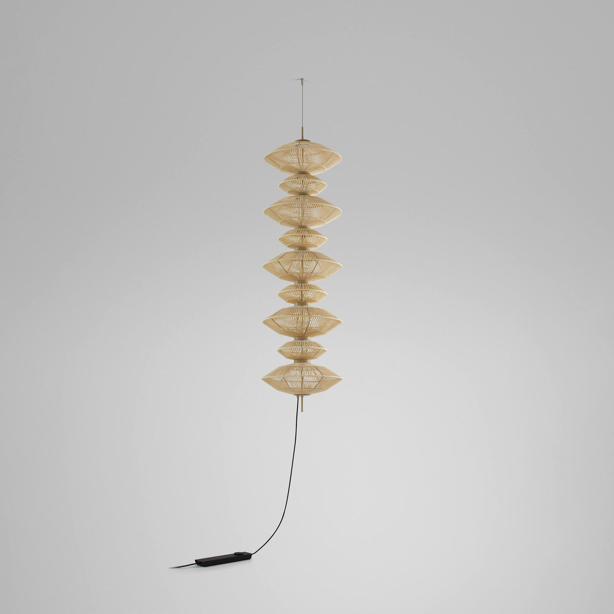 Yuyun S/9C/I fabric LED pendant light with nine stacked woven beige cotton tiers forming a tall column, hung from a slim cable against a plain light grey background.