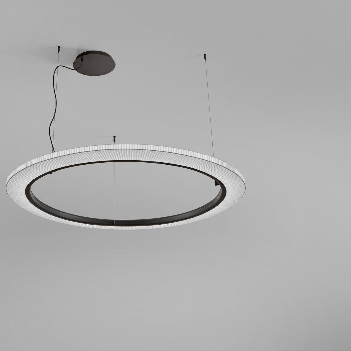 Roda S/150 Ribbon Ring LED pendant with pleated white translucent shade, dark inner ring, and cable-suspended black ceiling canopy against a grey background.