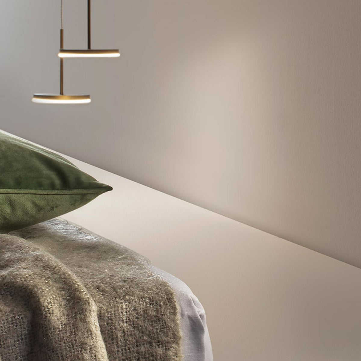 Bella Direct Aluminium LED Pendant Light in Brushed Titanium, two slim round disc fixtures at different heights above a bed with green cushion and knit throw.