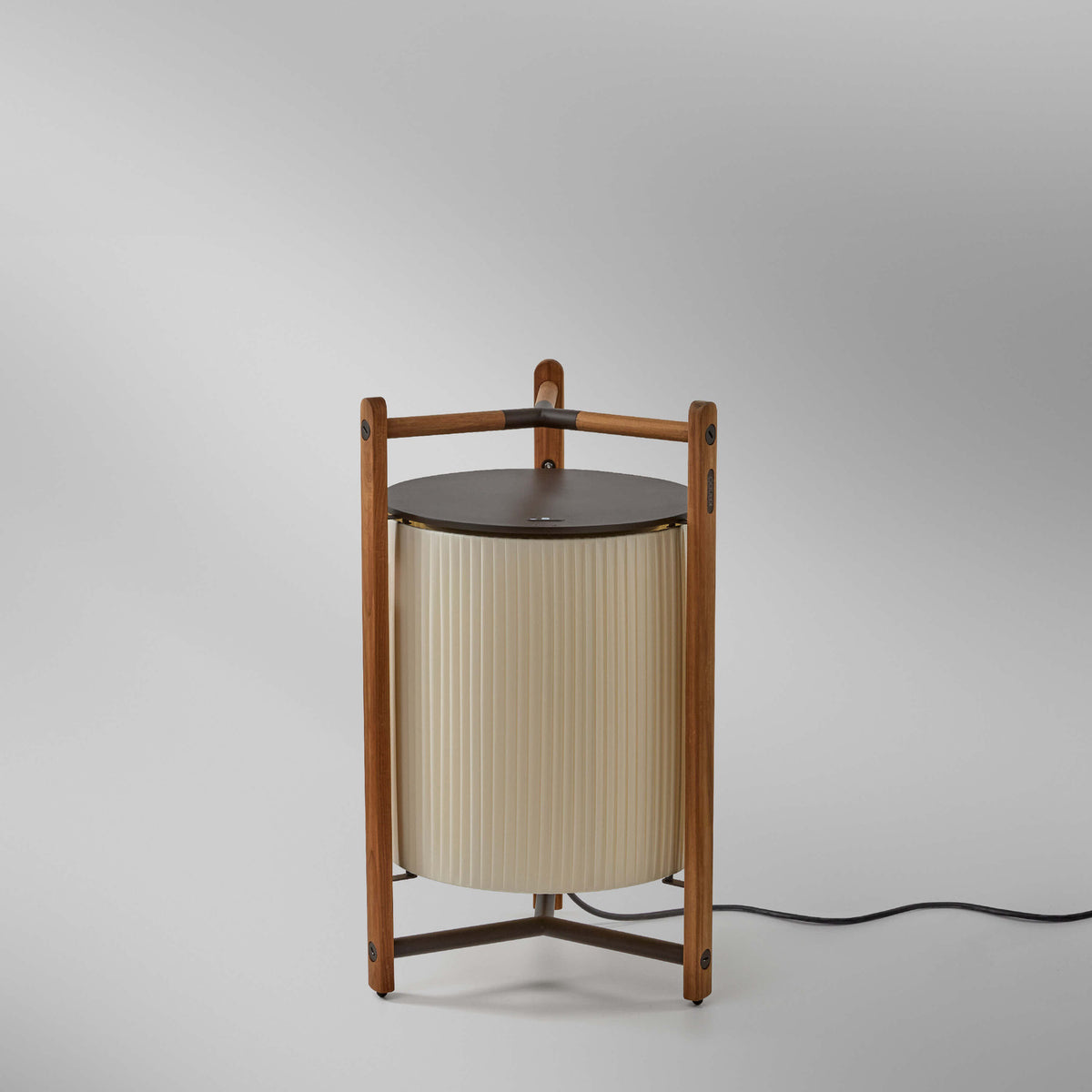 Kando P/76 Ribbon LED floor lamp with a cream pleated cylinder shade, teak wood tripod frame, and brown top disc, shown on a plain light grey background.