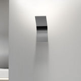 App Aluminium LED Wall Light with a slim curved metal plate in brushed silver finish, mounted on a light grey wall with soft downward glow.