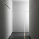 Bronx 300 recessed LED profile in black, shown as slim illuminated edge lines along wall and door frame in a minimalist grey corridor.