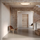 Bow LED Module Kit 50cm installed along ceiling and archway edges in a brick-walled hallway, its slim black profile curving gently where it bridges each opening.