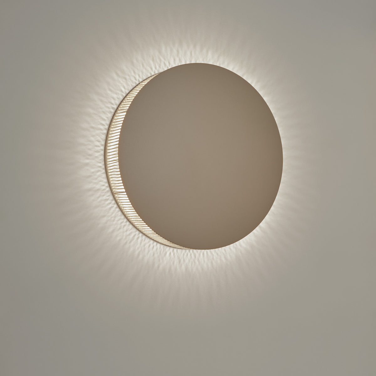 Helios A/02 round wall light in Oak Brown & Beige, flat disc face with a cotton thread edge casting a radiating LED glow on a plain light background.