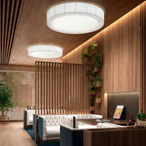 Urban PF/120 Ribbon LED Ceiling Light, two large round flush fixtures with ribbed drum sides and white diffusers, shown lit in a warm wood-panelled lounge.
