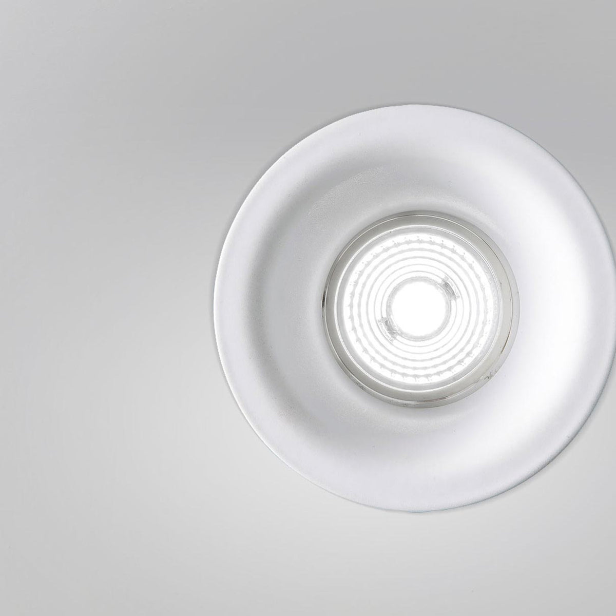 Joe Aluminium Round Recessed LED Downlight 9cm in white, close-up of deep flared trim and ribbed lens with warm white light, shown on a plain grey background.