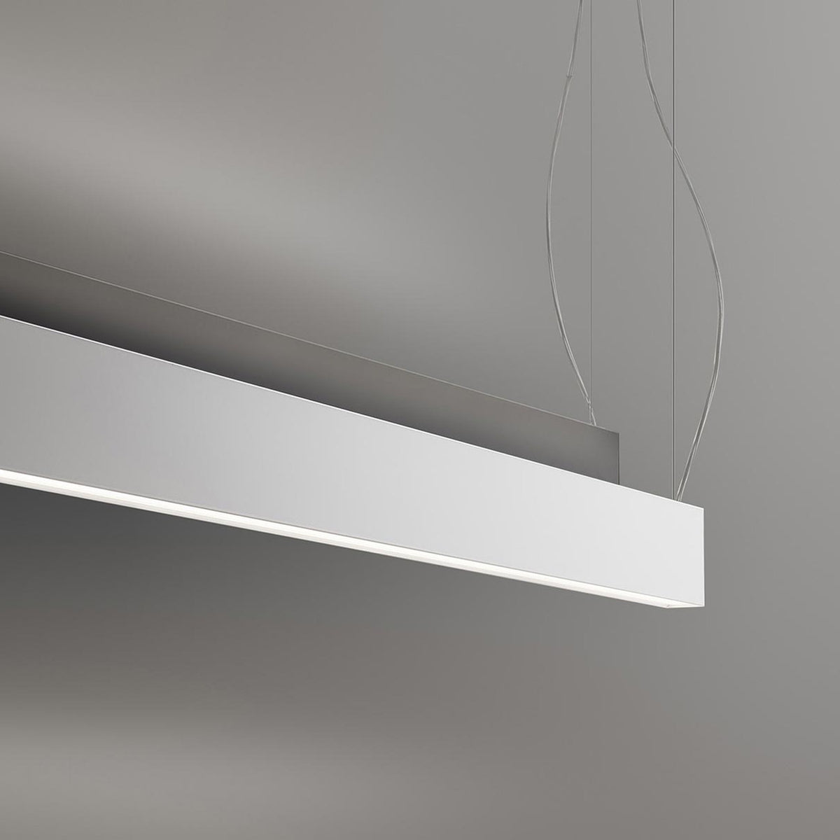 Giano Aluminium Linear LED Pendant Light, a slim white rectangular bar suspended on fine wires with a narrow underside diffuser, shown against a plain grey background.