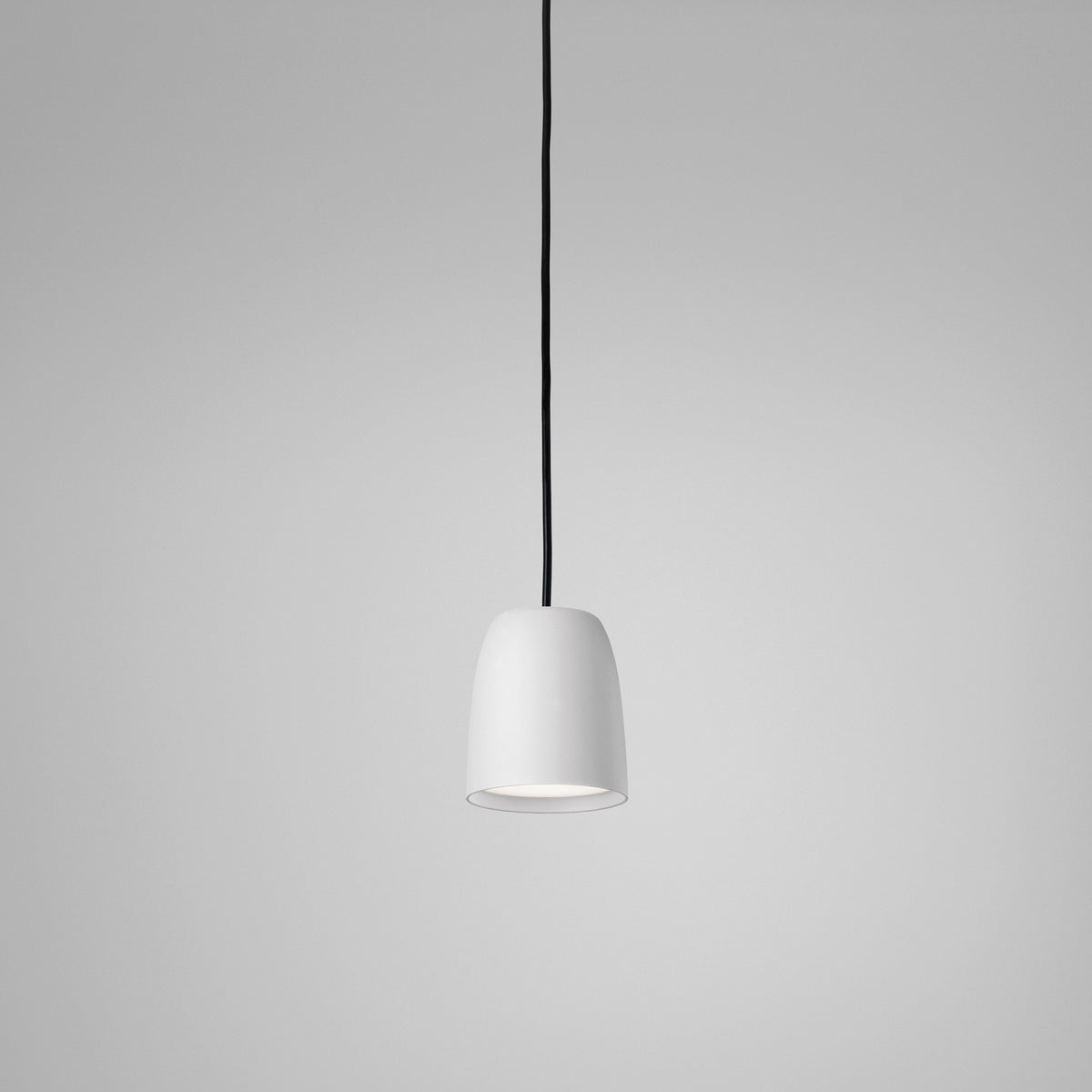 Nut S/10 pendant light with a small bell-shaped white textured shade, stainless steel and aluminium construction, black cord, shown on a plain grey background.