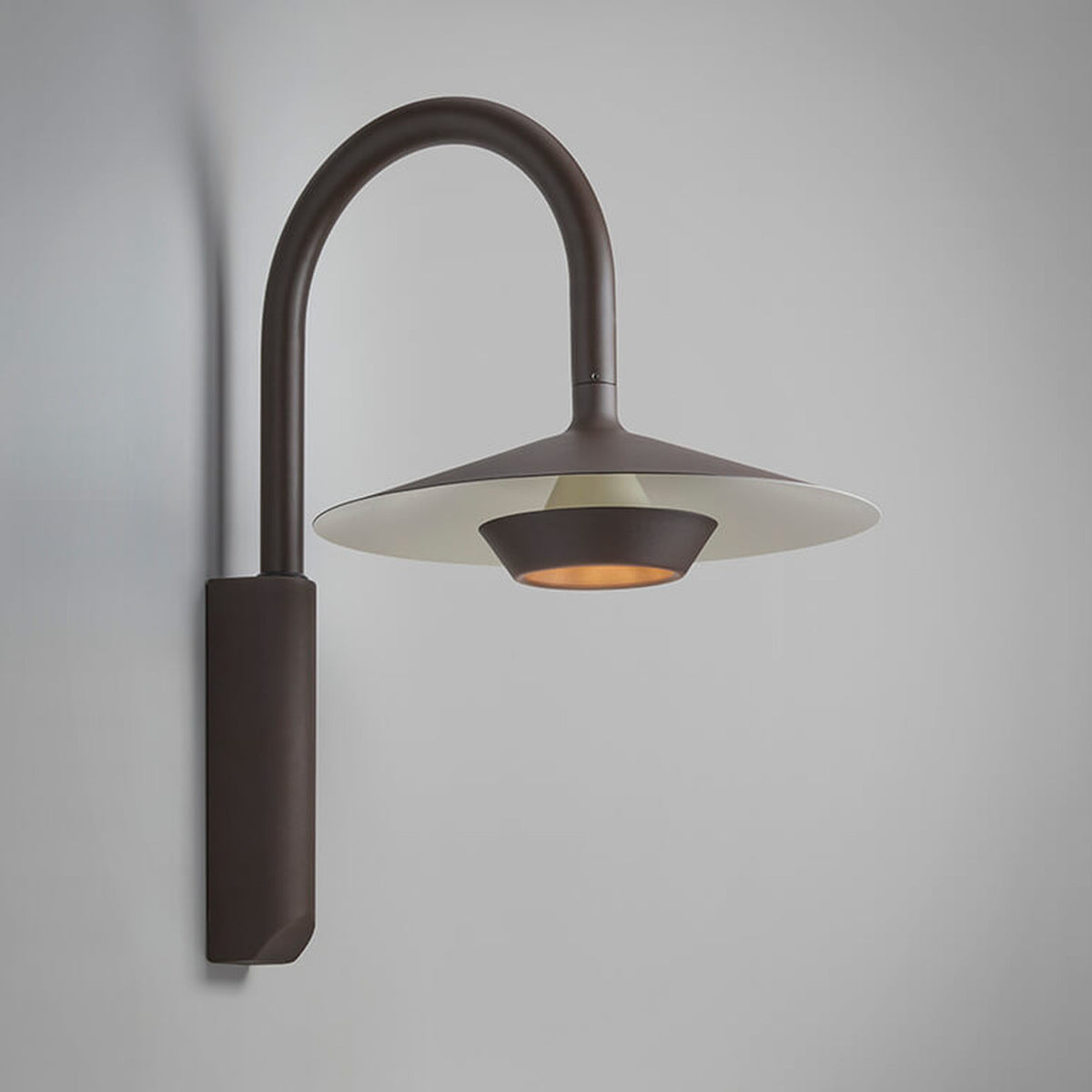 Fanalet A/02 aluminium outdoor wall light with tall arched arm, flat wide shade in graphite brown with white underside, integrated LED, shown on a plain grey background.