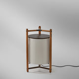 Kando P/76 Ribbon LED floor lamp with a pleated white translucent cylindrical shade, dark cap, and teak wood frame with tripod base, on a plain light background.
