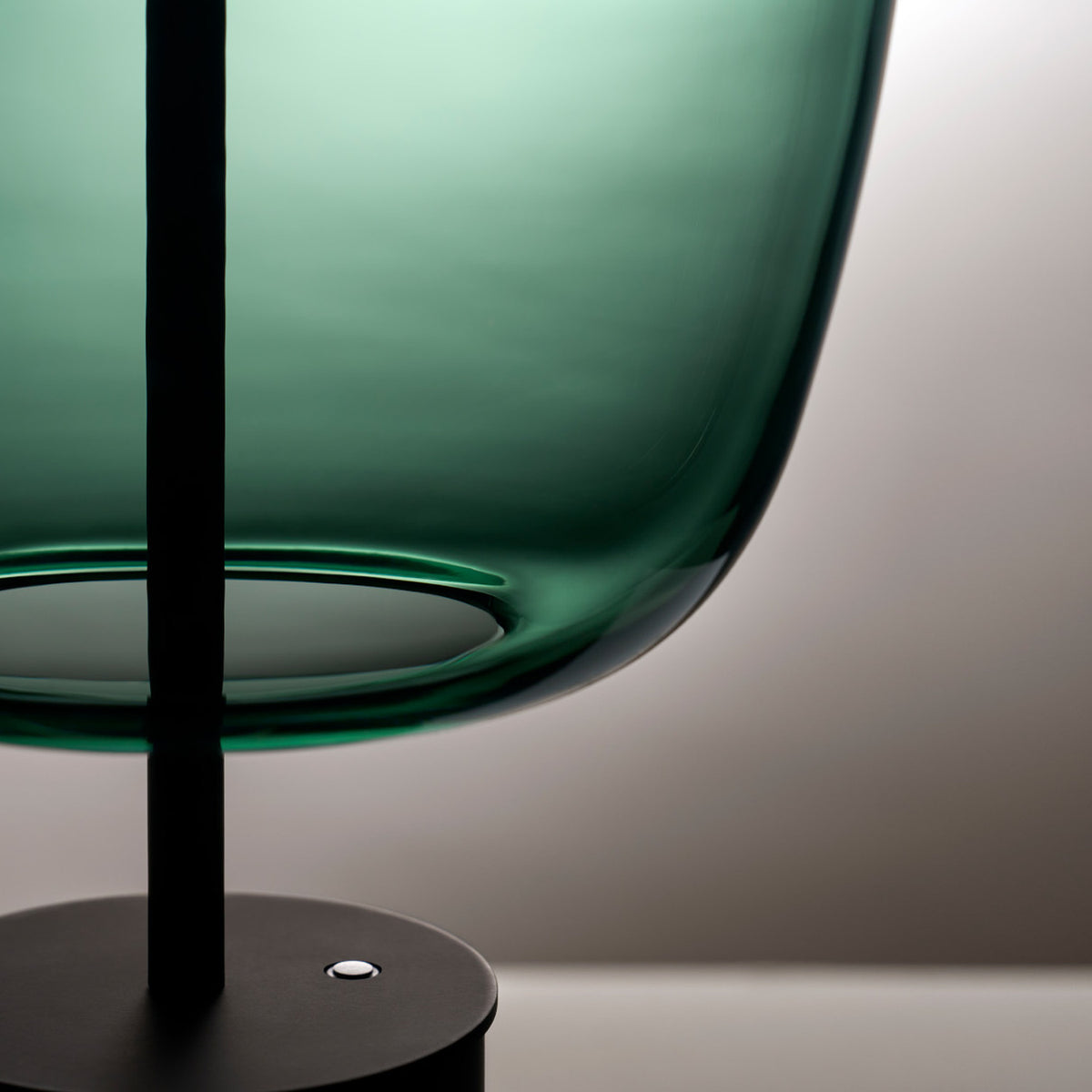 Close-up of the Adamas 23 Forest Green Glass LED Table Lamp, showing the rounded glass shade's faceted edge, slim black rod, and matt black base with switch.