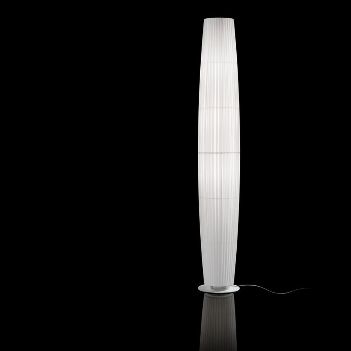 Maxi P/03 Ribbon Cylinder Floor Lamp with a tall, tapered white pleated ribbon shade on a round base, set against a plain black background.