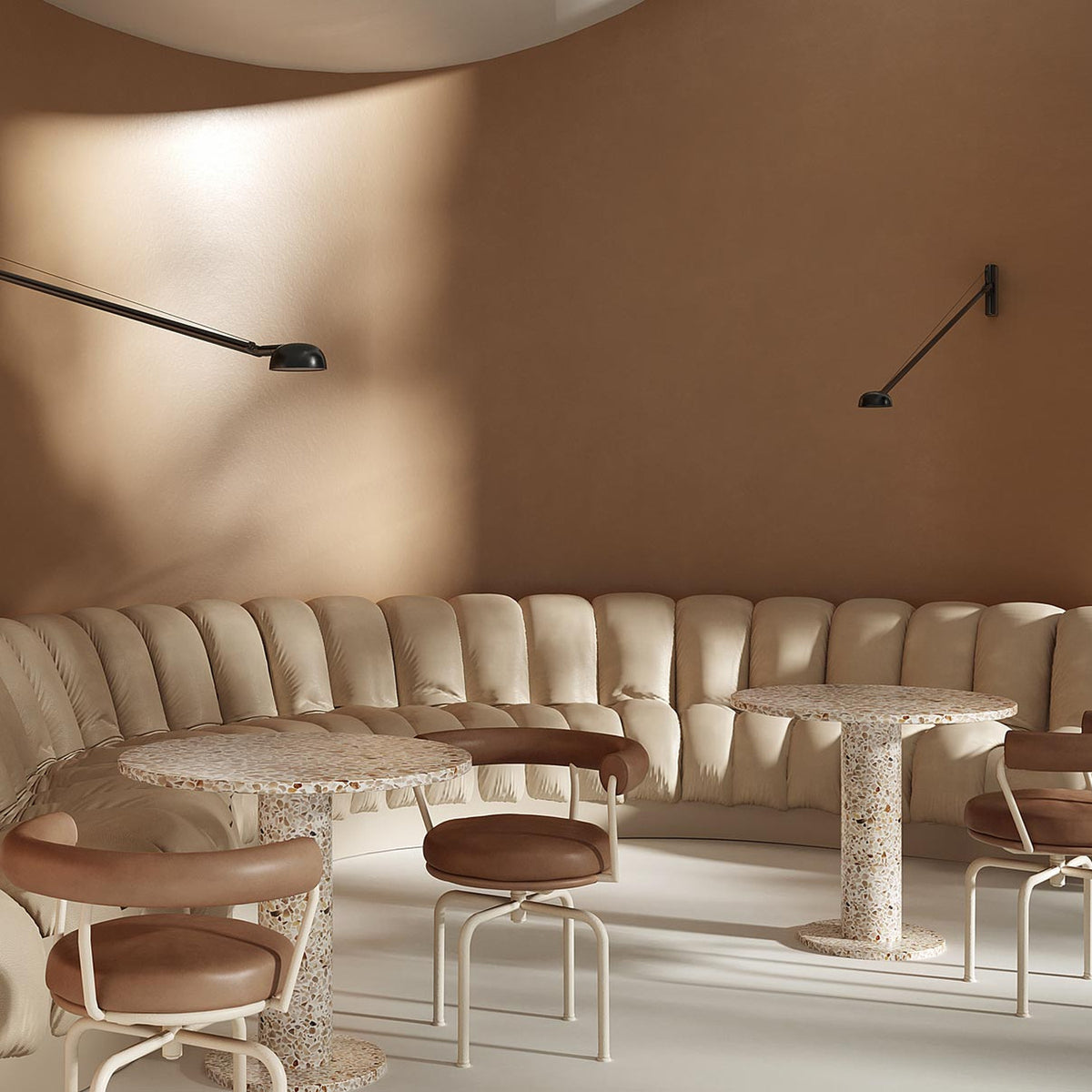 Opuntia 180 Aluminium LED Wall Lights in matte black with slim extended arms and dome heads, mounted on a curved tan wall above a beige banquette seating area.