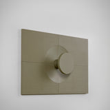 Arid Wall Light Tile in Textured Olive Grey, a fluted aluminium panel with a central circular cut-out and cylindrical light detail, shown at an angle against a plain white background.