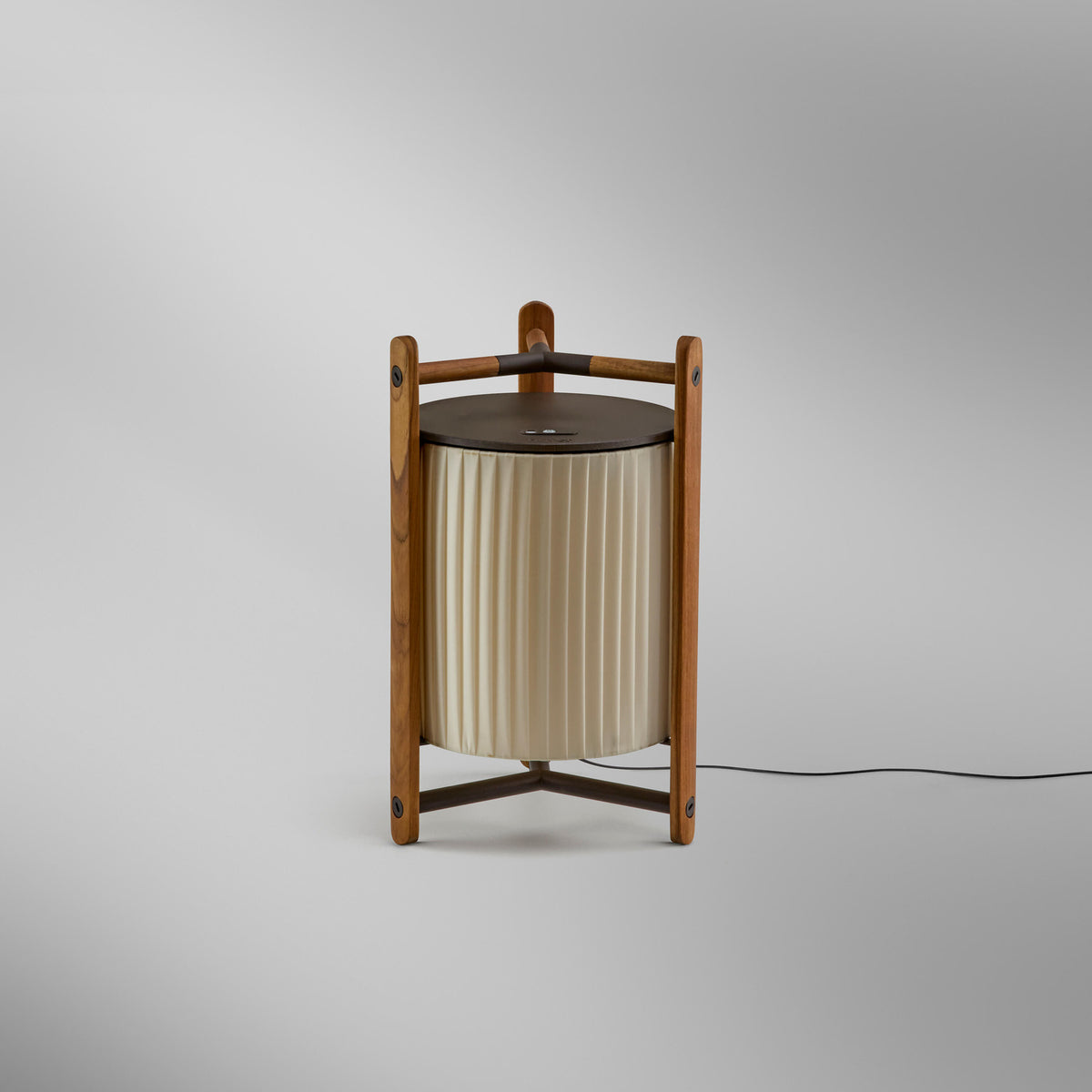 Kando M/40 table lamp with pleated cream ribbon shade inside an open teak wood frame, dark top cap, integrated LED, shown on a plain light grey background.